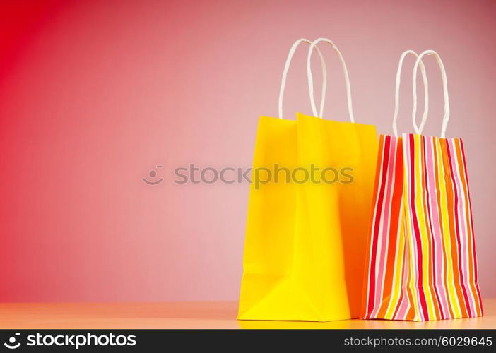 Colourful paper shopping bags against gradient background