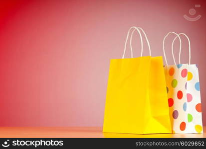 Colourful paper shopping bags against gradient background