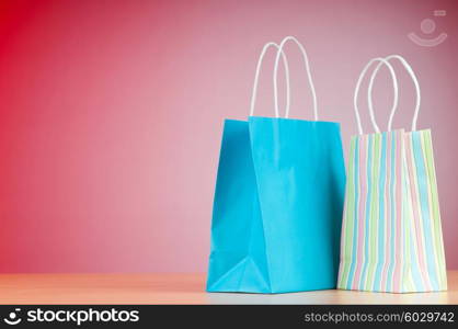 Colourful paper shopping bags against gradient background