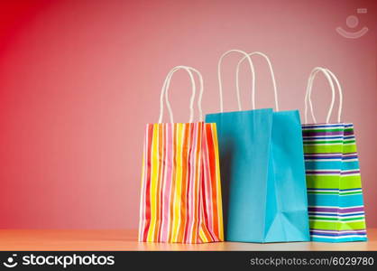 Colourful paper shopping bags against gradient background