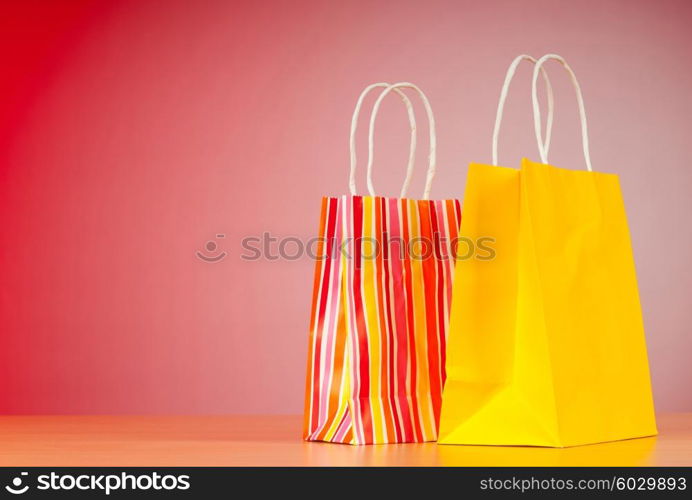 Colourful paper shopping bags against gradient background