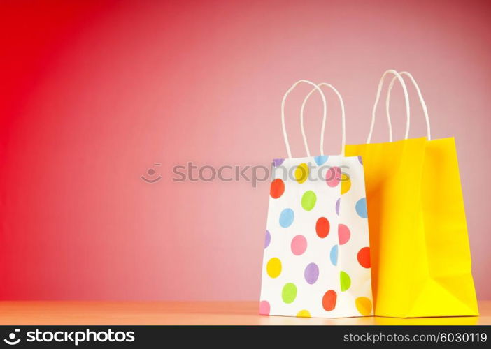 Colourful paper shopping bags against gradient background