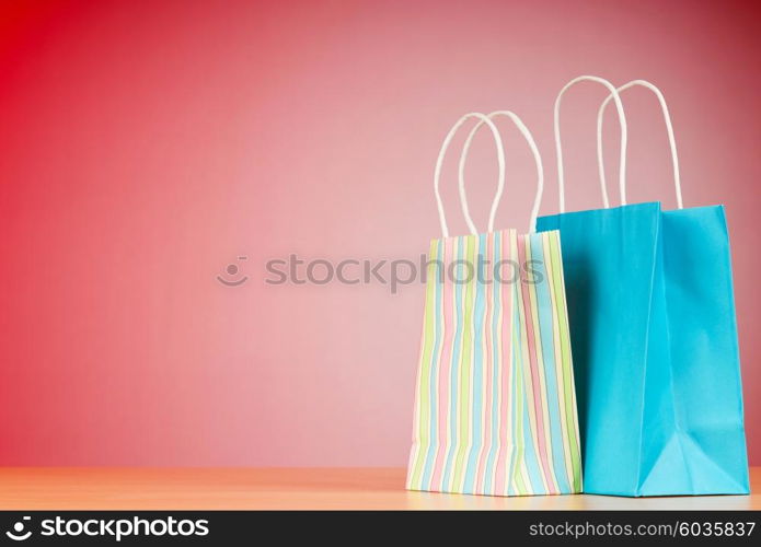 Colourful paper shopping bags against gradient background