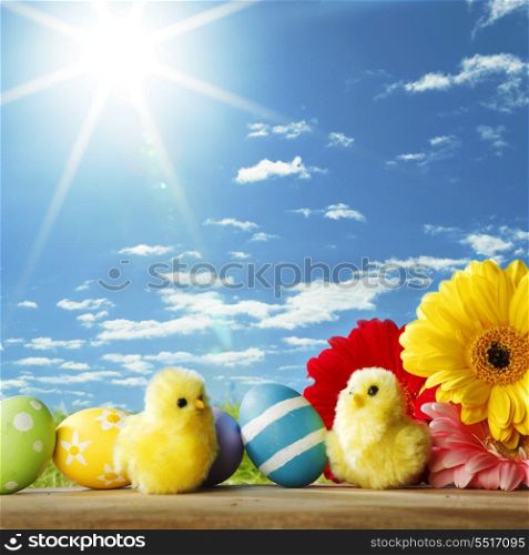 Colourful traditional Easter eggs arranged with colourful Gerbera daisies and toy chicks