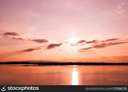 Colourful vibrant sunset over lake at Nong Han Sakon Nakhon - Thailand. Peaceful twilight scenery aginst sunset