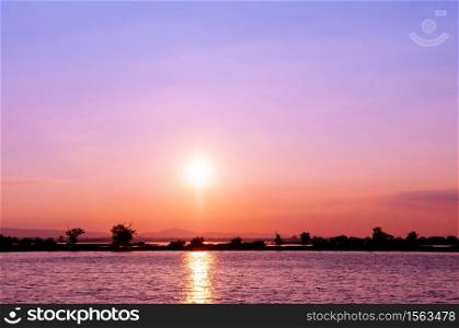Colourful vibrant sunset over lake at Nong Han Sakon Nakhon - Thailand. Peaceful twilight scenery aginst sunset