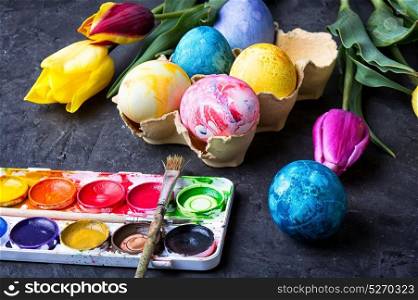 colouring eggs for eastertime. Multicolored easter eggs, set of watercolors and tulips