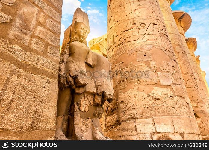 Columns with hyerogliphs and ruined satue in Karnak Temple of Luxor, Egypt. Columns and statue in Karnak Temple