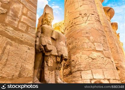 Columns with hyerogliphs and ruined satue in Karnak Temple of Luxor, Egypt. Columns and statue in Karnak Temple