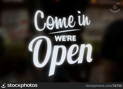 come in we are open sign on glass of coffee shop window