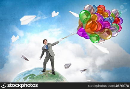 Comedian man with color balloons. Young funny man in hat with balloons presenting celebration concept. Elements of this image are furnished by NASA