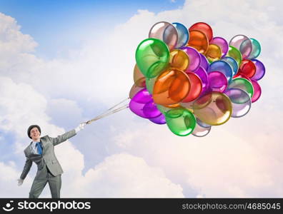 Comedian man with color balloons. Young funny man in hat with balloons presenting celebration concept