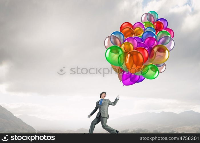 Comedian man with color balloons. Young funny man in hat with balloons presenting celebration concept