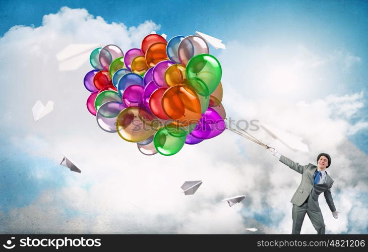 Comedian man with color balloons. Young funny man in hat with balloons presenting celebration concept