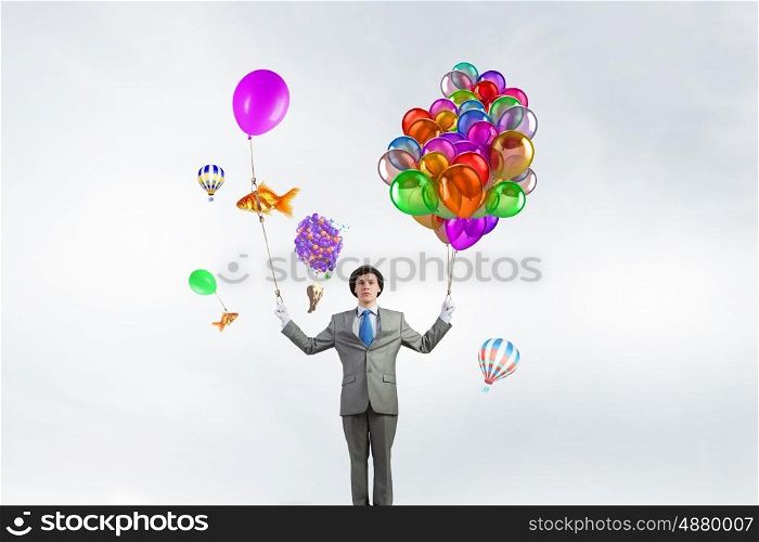 Comedian man with color balloons. Young funny man in hat with balloons presenting celebration concept