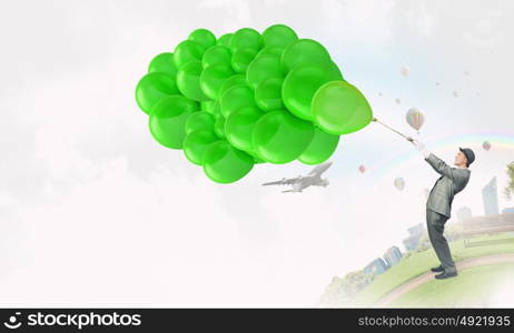 Comedian man with color balloons. Young funny man in hat with balloons presenting celebration concept