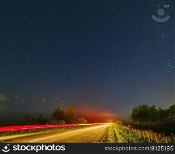 Comet Neowise C2020 F3 as it flies overhead in the summer sky over over meadow near countryside road, Lviv Region, Ukraine.