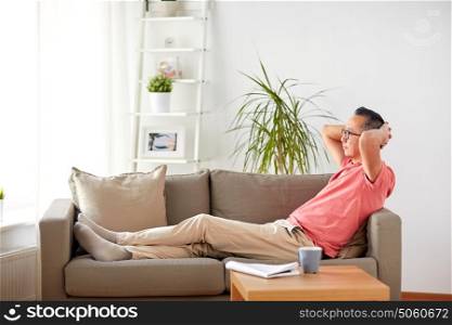 comfort and people concept - man in glasses relaxing on sofa at home. man in glasses relaxing on sofa at home