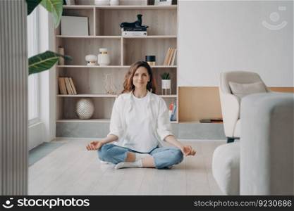 Comfort and serenity. Relaxed hispanic woman is practicing yoga and meditation on floor at home. Lotus pose, morning gymnastics, body and soul in harmony. Concentration and consciousness concept.. Comfort and serenity. Relaxed hispanic woman is practicing yoga and meditation on floor at home.