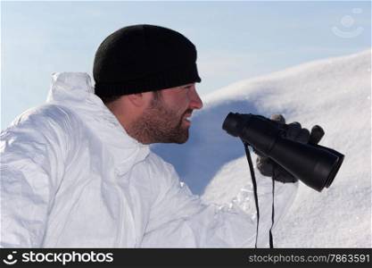 Commandos in white camouflage looking through binoculars in the mountains on the white snow. Portrait in Profile