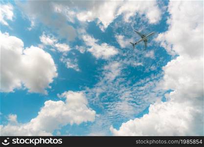 Commercial airline flying on blue sky and white cumulus clouds. Under view airplane flying. Passenger plane travel bubble flight. Vacation travel abroad after coronavirus crisis. Air transportation.
