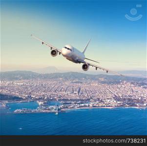 Commercial airplane flying above Barcelona city, in beautiful sunset light