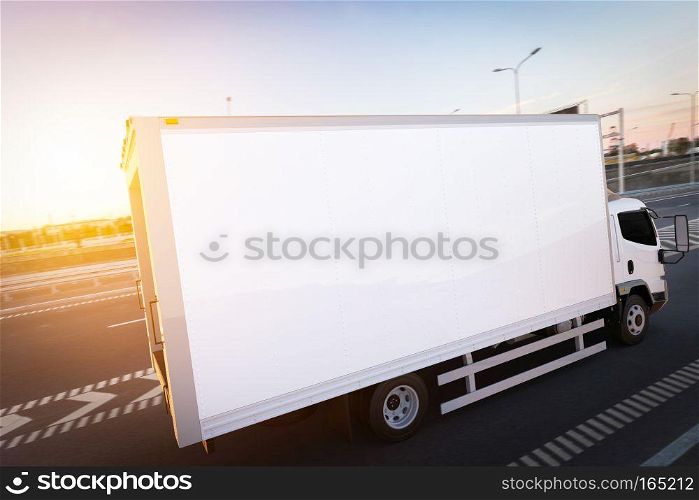 Commercial cargo delivery truck with blank white trailer driving on highway. Generic, brandless vehicle design. 3D rendering. Commercial cargo delivery truck with blank white trailer driving on highway.