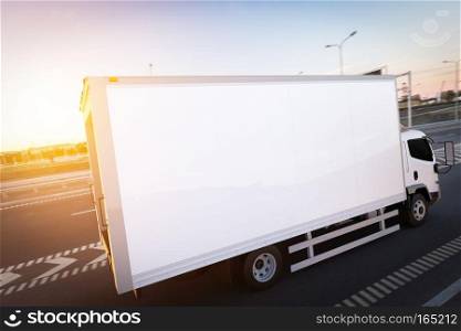 Commercial cargo delivery truck with blank white trailer driving on highway. Generic, brandless vehicle design. 3D rendering. Commercial cargo delivery truck with blank white trailer driving on highway.
