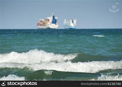 Commercial container ship on blue sky and big waves
