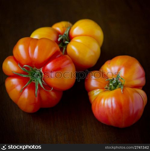 Commercial Photography. 3 Large, ripe heirloom tomatoes shot on a wood background.