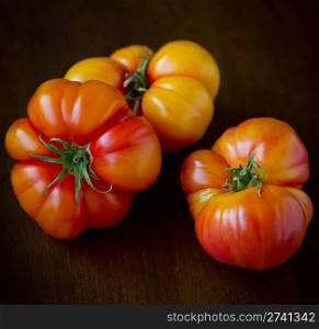 Commercial Photography. 3 Large, ripe heirloom tomatoes shot on a wood background.