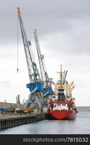 Commercial ship moored of at rotterdam Harbor next to large cane