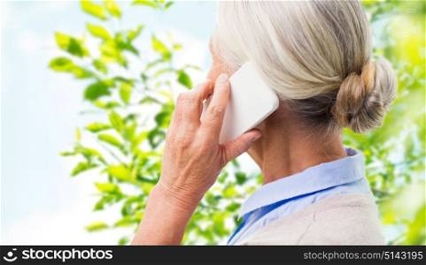 communication, age and people concept - close up of senior woman with smartphone calling over window and green natural background. close up of senior woman calling on smartphone