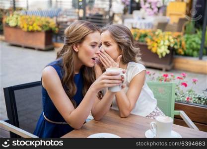 communication and friendship concept - smiling young women drinking coffee and gossiping at street cafe. smiling young women drinking coffee and gossiping