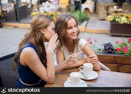communication and friendship concept - smiling young women drinking coffee and gossiping at street cafe. smiling young women drinking coffee and gossiping
