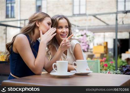 communication and friendship concept - smiling young women drinking coffee and gossiping at street cafe. smiling young women drinking coffee and gossiping. smiling young women drinking coffee and gossiping