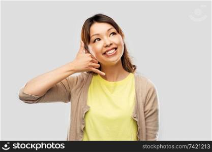 communication and people concept - happy asian young woman making phone calling gesture over pink background. african asian making phone call gesture