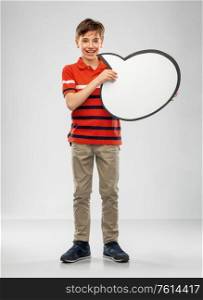 communication and people concept - smiling boy holding blank speech bubble over grey background. boy holding speech bubble