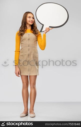 communication and people concept - smiling teenage girl holding blank speech bubble over grey background. teenage girl holding speech bubble