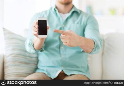 communication, business, home and technology concept - close up of man showing smartphone screen sitting on couch at home