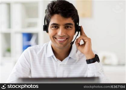 communication, business, people and technology concept - businessman or helpline operator with headset and laptop computer at office. businessman with headset and computer at office