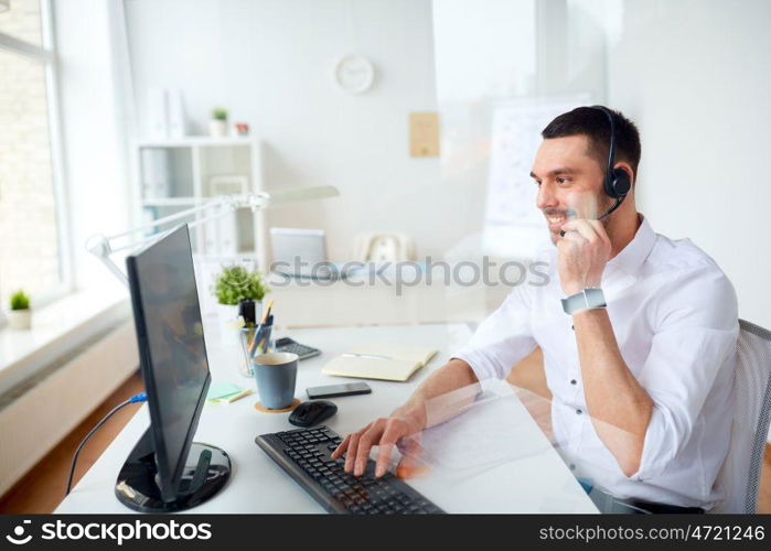 communication, business, people and technology concept - smiling businessman or helpline operator with headset and computer typing at office. businessman with headset and computer at office. businessman with headset and computer at office