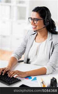 communication, business, people and technology concept - smiling businesswoman or helpline operator with headset typing on keyboard at office. businesswoman with headset and keyboard at office. businesswoman with headset and keyboard at office