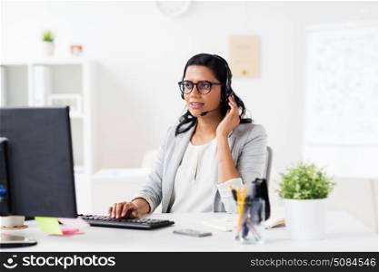 communication, business, people and technology concept - smiling businesswoman or helpline operator with headset and computer talking and typing at office. businesswoman with headset and computer at office. businesswoman with headset and computer at office
