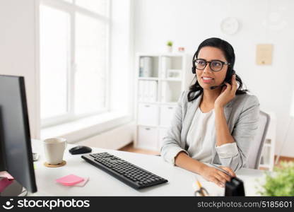 communication, business, people and technology concept - smiling businesswoman or helpline operator with headset and computer talking and typing at office. businesswoman with headset and computer at office