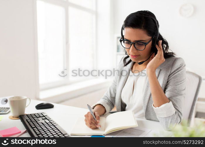 communication, business, people and technology concept - smiling businesswoman or helpline operator with headset talking at office. businesswoman with headset talking at office