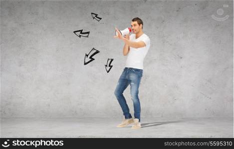 communication concept - handsome man with megaphone over concrete wall