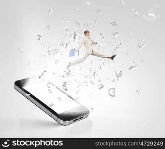 Communication concept. Image of businessman jumping out of mobile phone