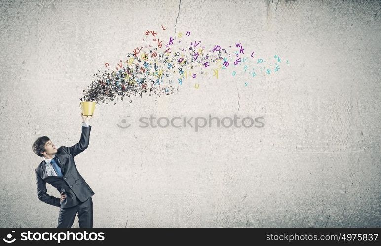 Communication concept. Young businessman holding yellow bucket with colorful letters