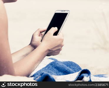 Communication concept. Young woman spending time on summer beach texting messages on smartphone. Girl using mobile phone.. Woman on beach texting on smartphone.